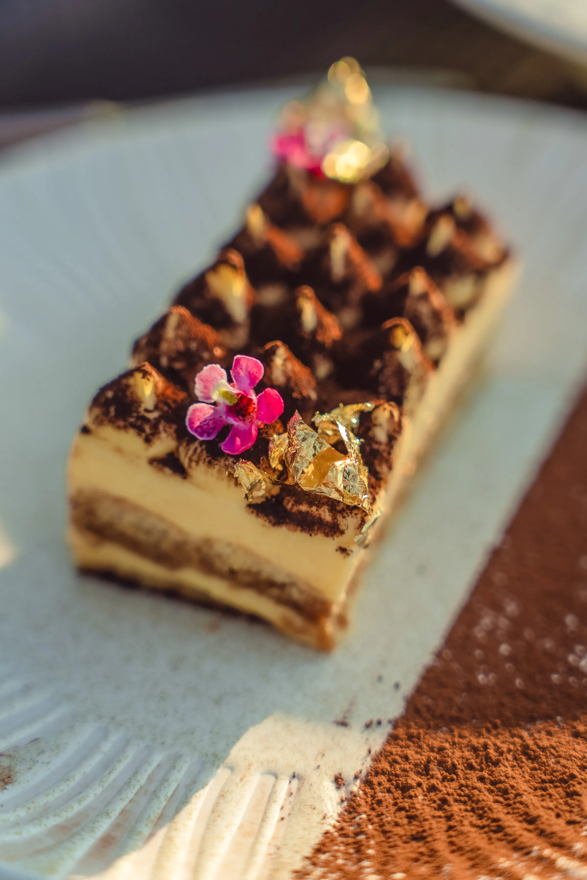 Artisan tiramisu garnished with edible flower and gold leaf