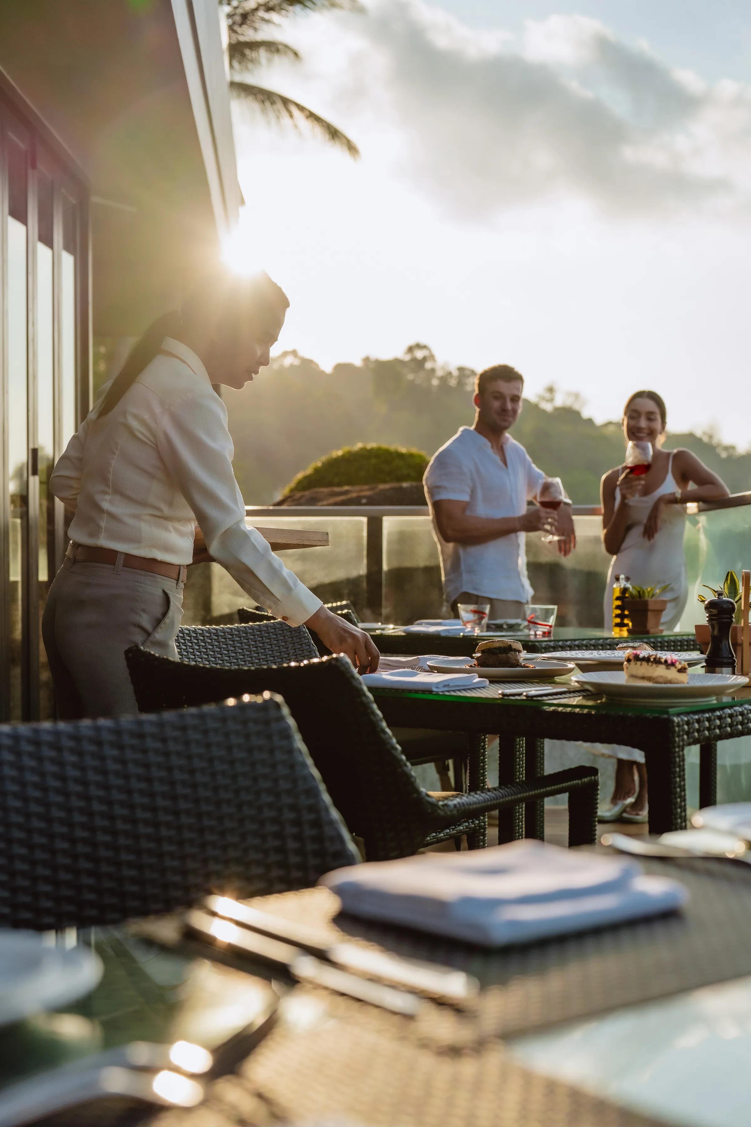 Waiter setting up a table with beautiful sunset backdrop